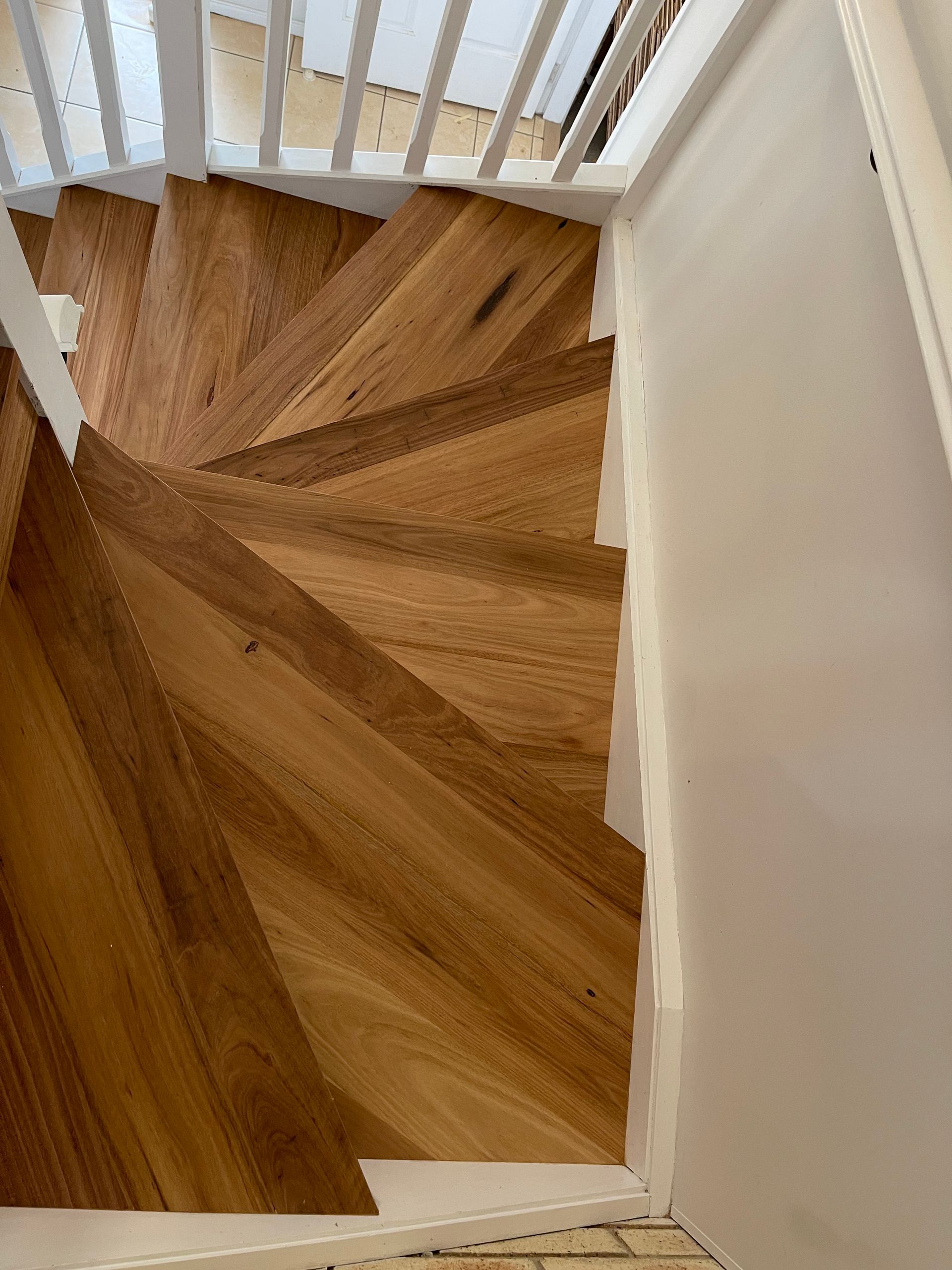 Wooden staircase with geometric pattern, white trim, viewed from above.