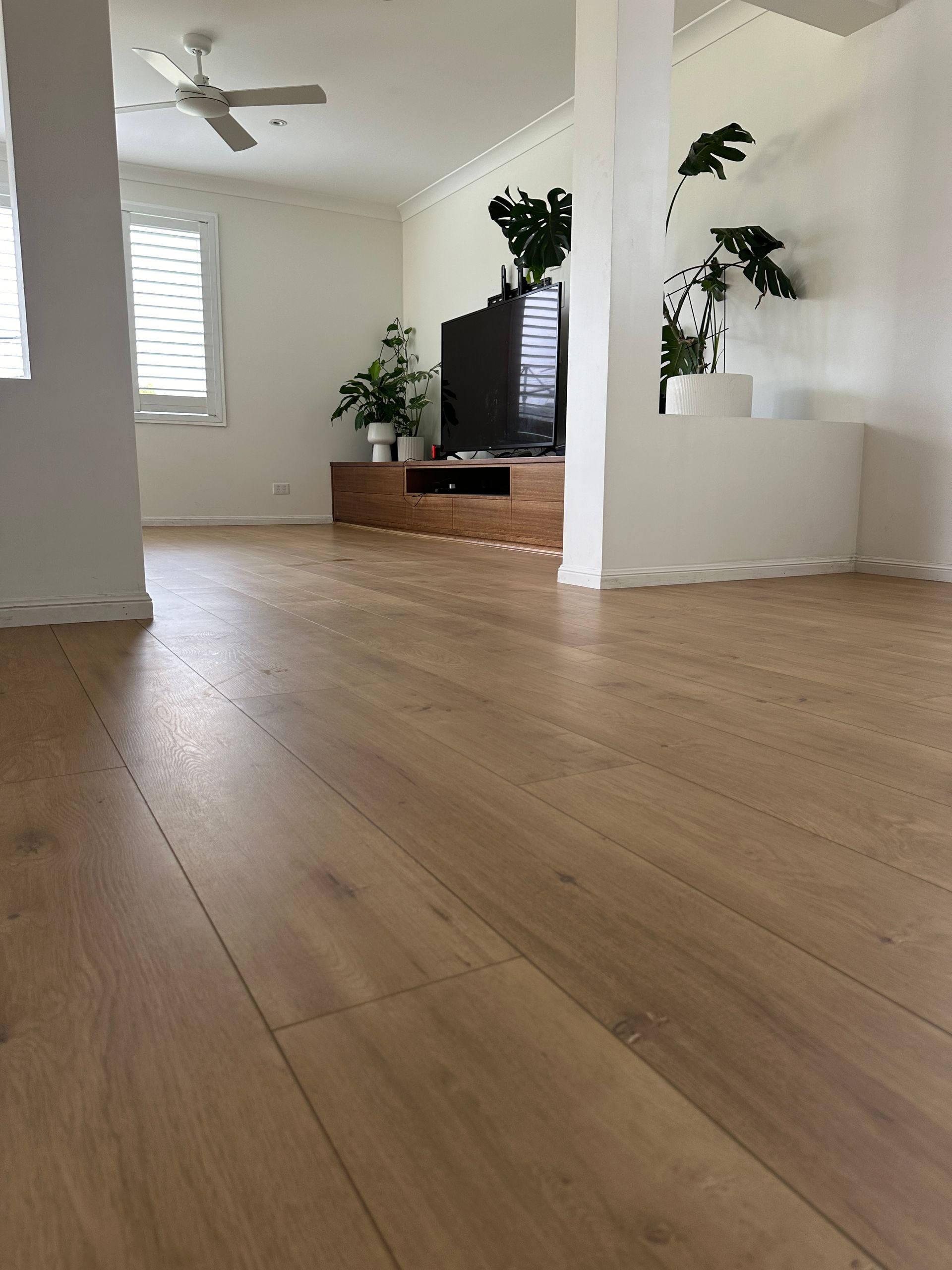 A living room with a wooden floor and a ceiling fan.