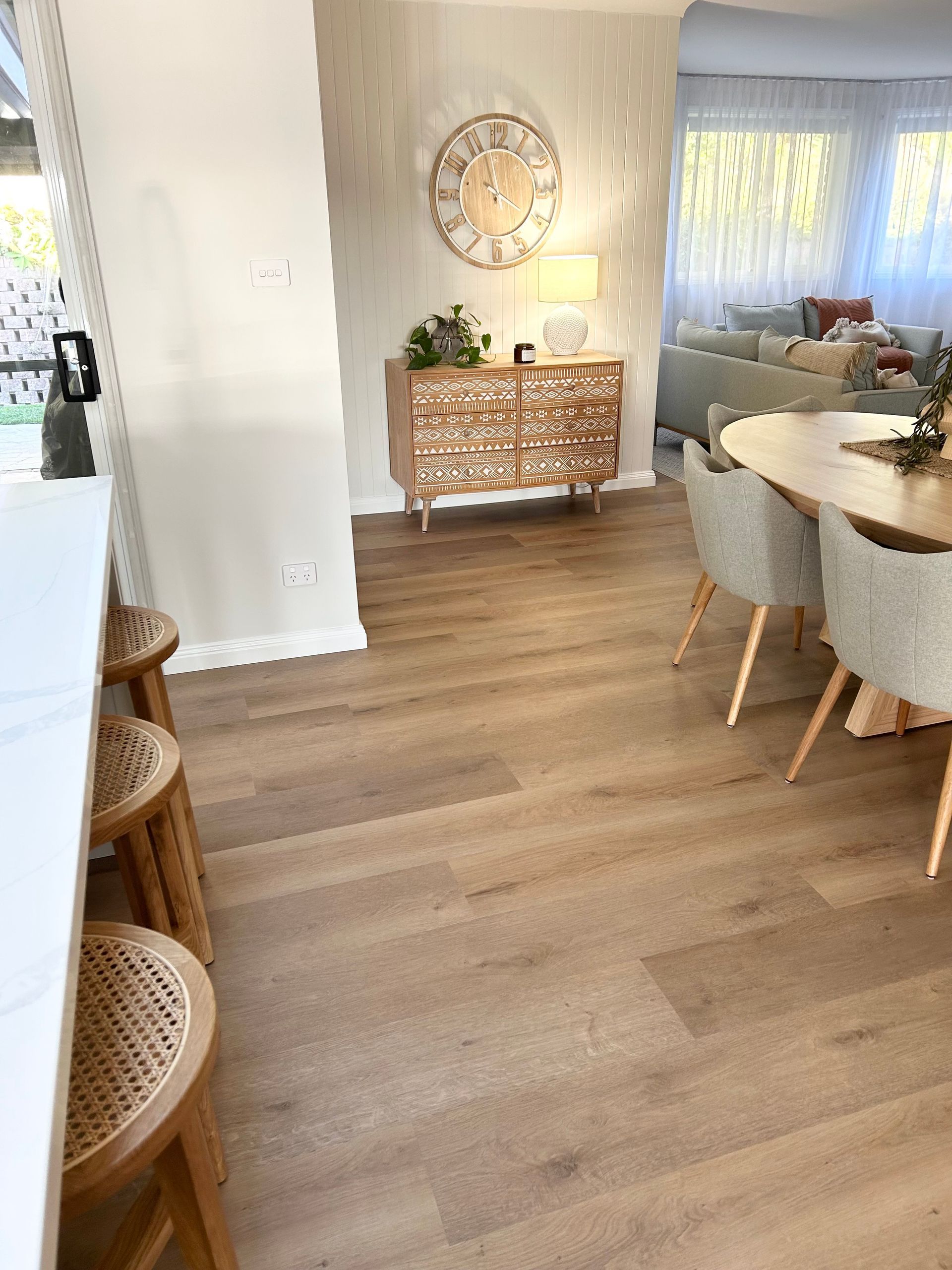 A living room with hardwood floors and a clock on the wall.