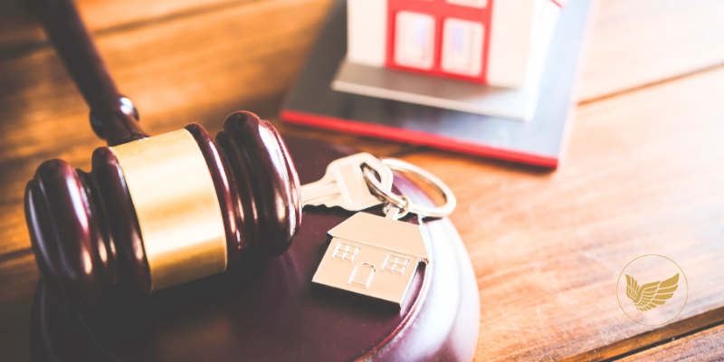 A judge 's gavel , keys and a model house on a wooden table.