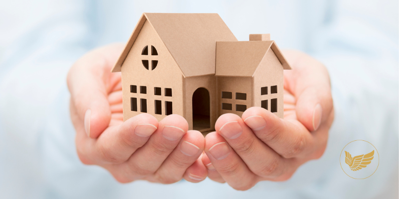 A person is holding a model house in their hands.