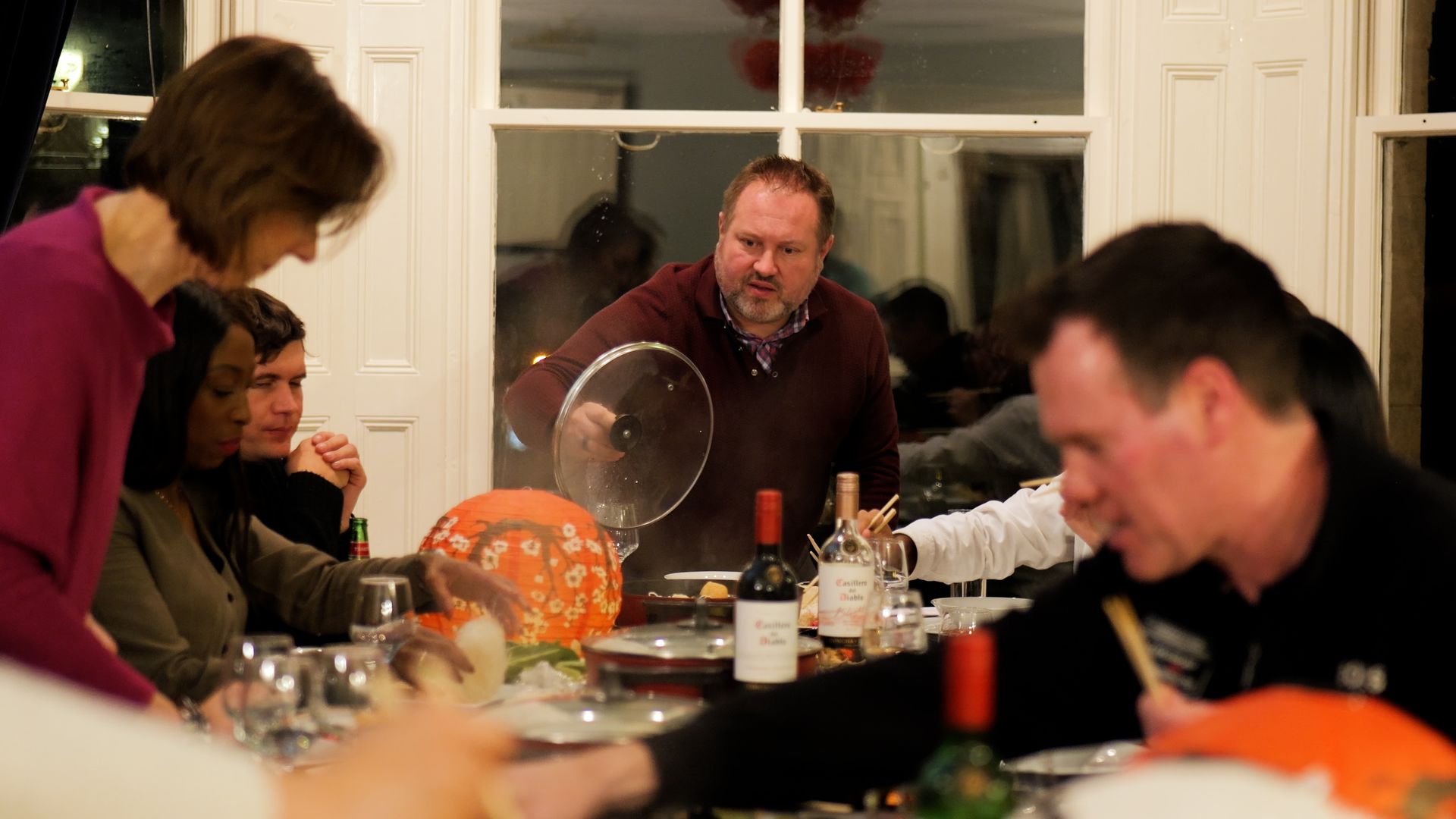 A group of people are sitting at a table eating food and drinking wine.