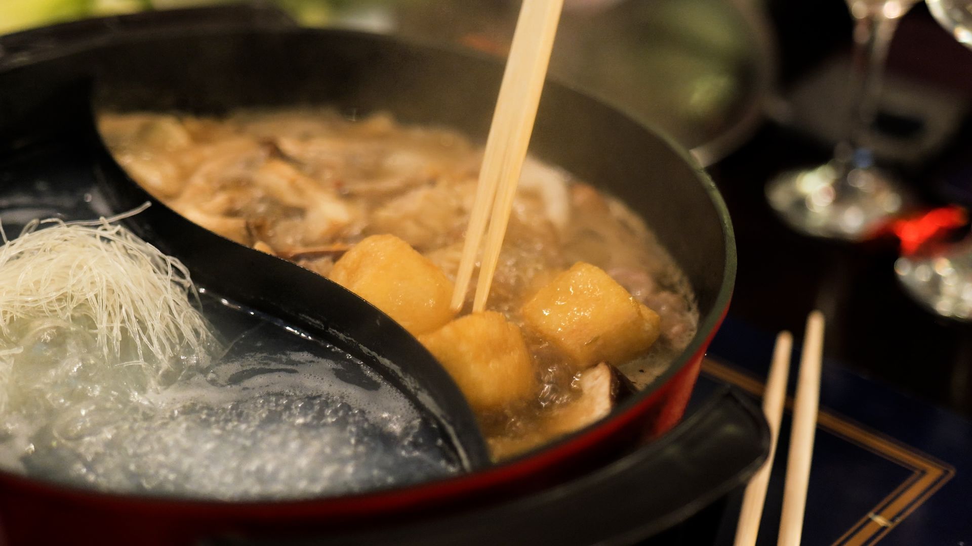 A pot of food is being stirred with chopsticks.