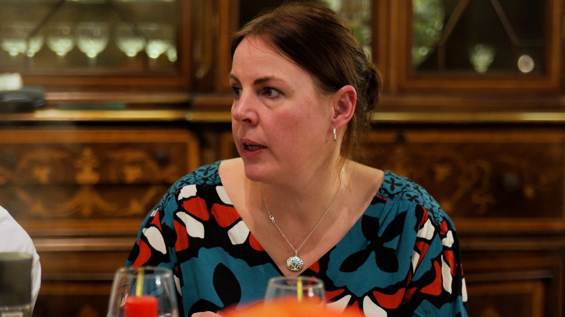 A woman is sitting at a table with wine glasses and a candle.