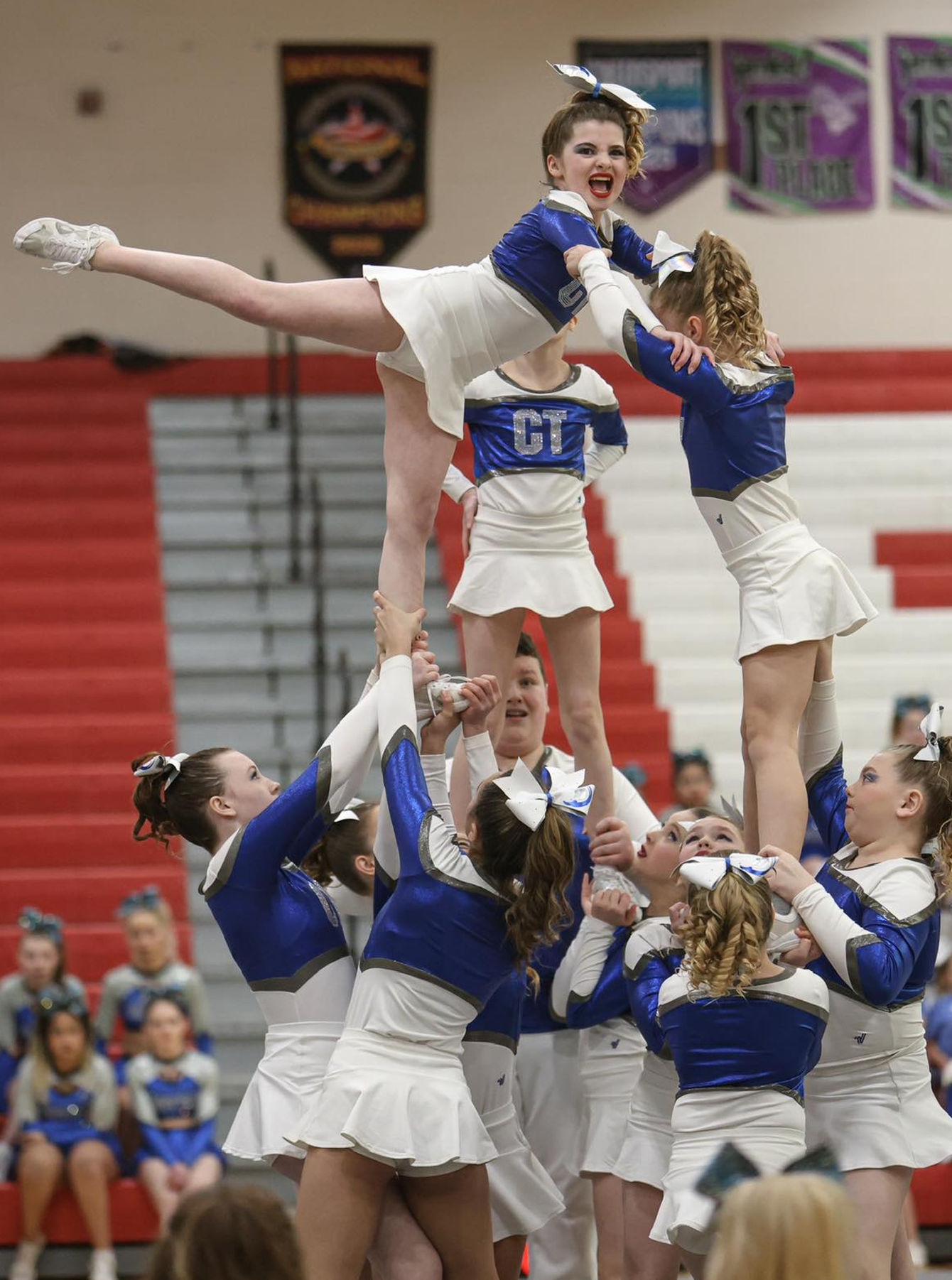 A group of cheerleaders are performing a stunt in a gym.