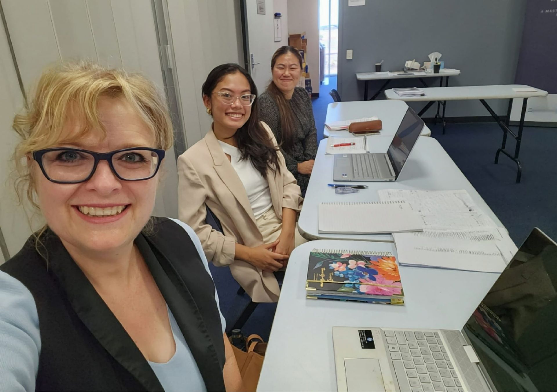 Three women are sitting at a table with laptops.