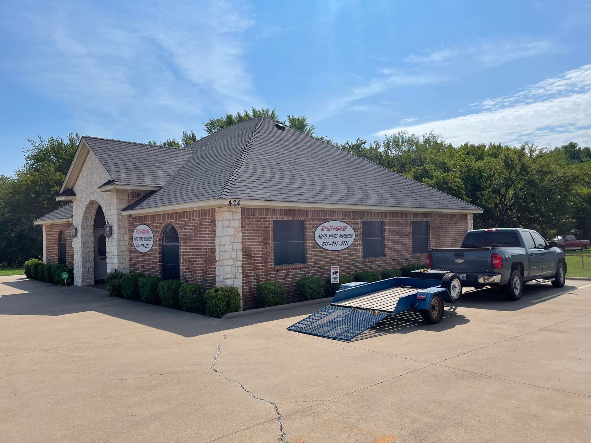 Brick building with a trailer and truck parked outside under a blue sky.