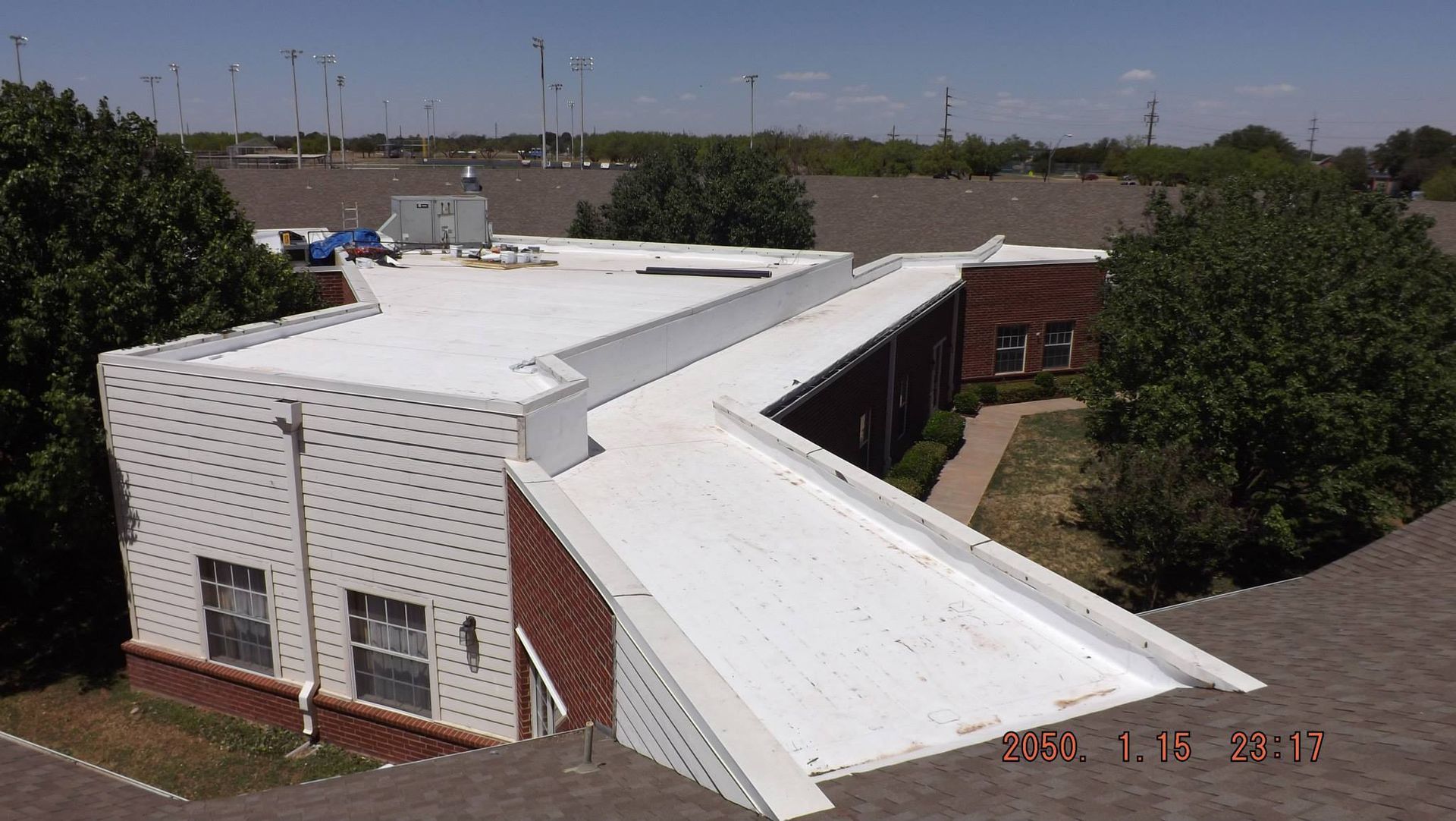 A white flat roofed brick building with a zig-zag shape under a sunny sky.