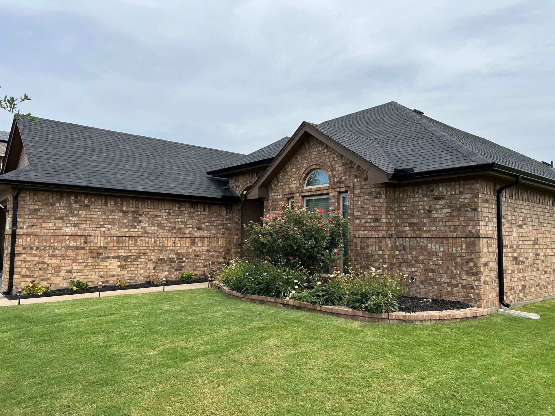 Brick house with a dark roof and green lawn.
