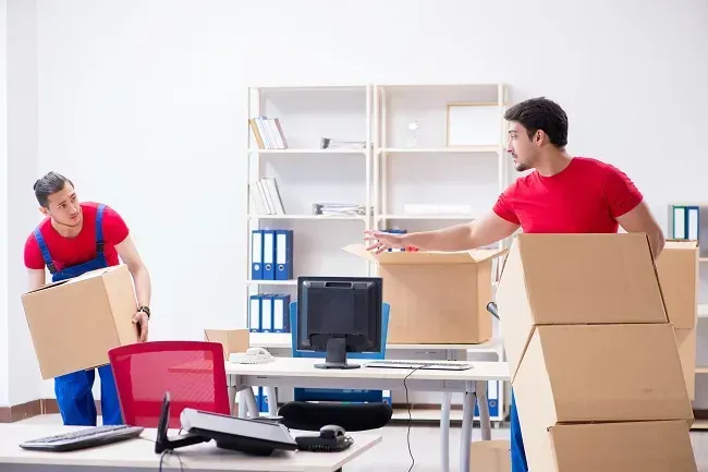 A professional mover carefully placing a wrapped furniture piece into a secure storage unit.
