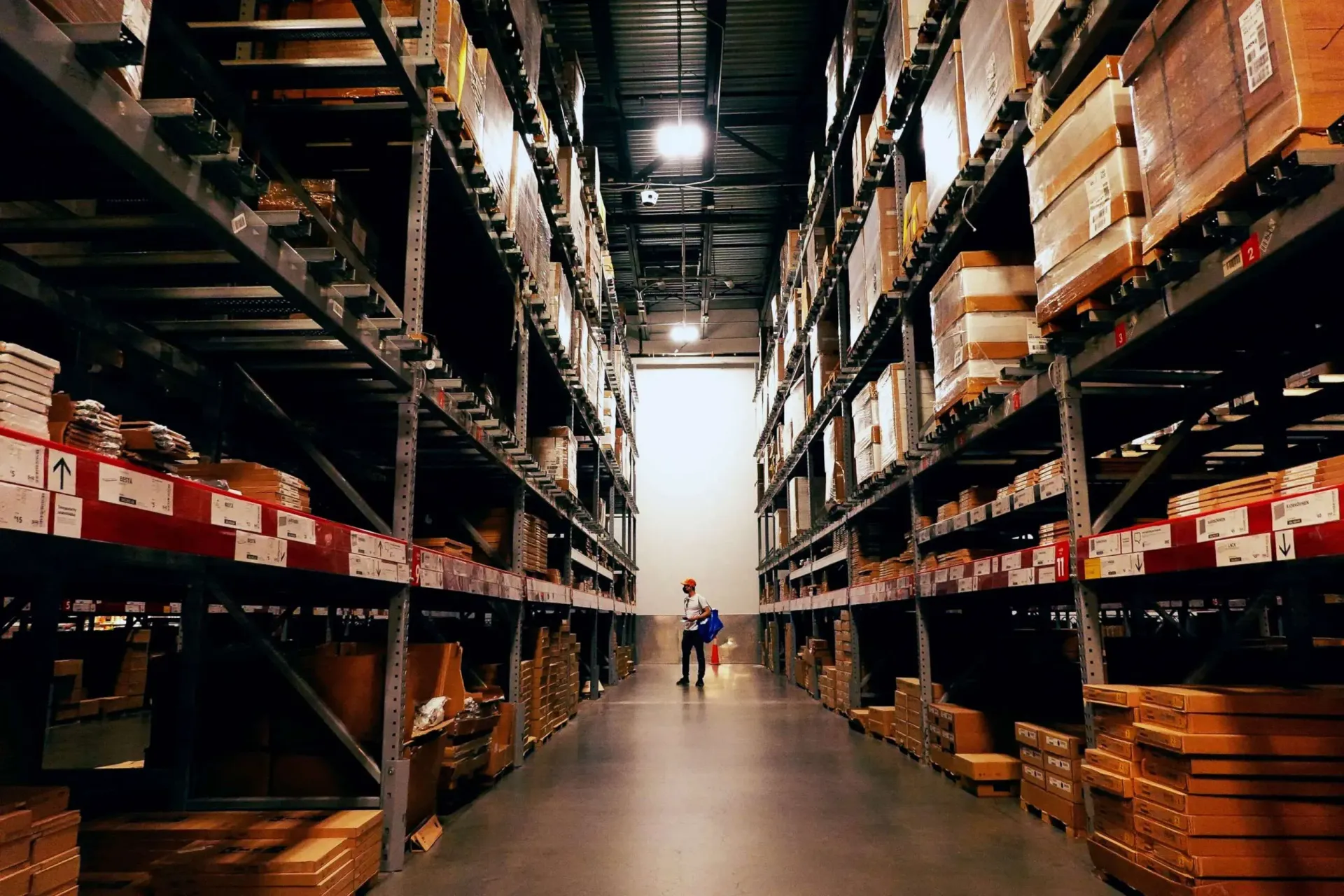 A man is walking through a warehouse filled with lots of shelves and boxes.