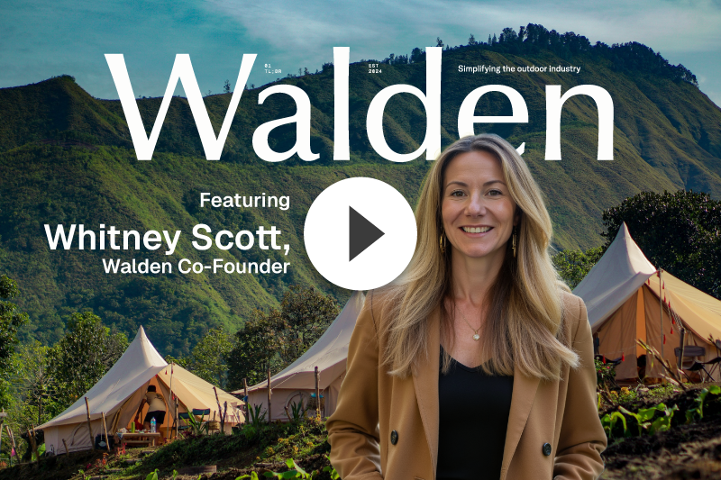 Woman smiling in front of glamping tents, mountains, and Walden logo.