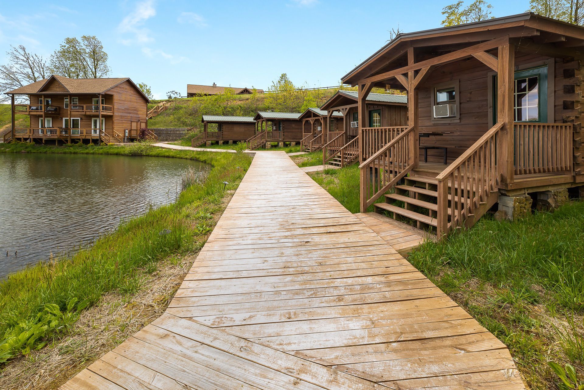 A wooden walkway leading to a row of cabins next to a lake.