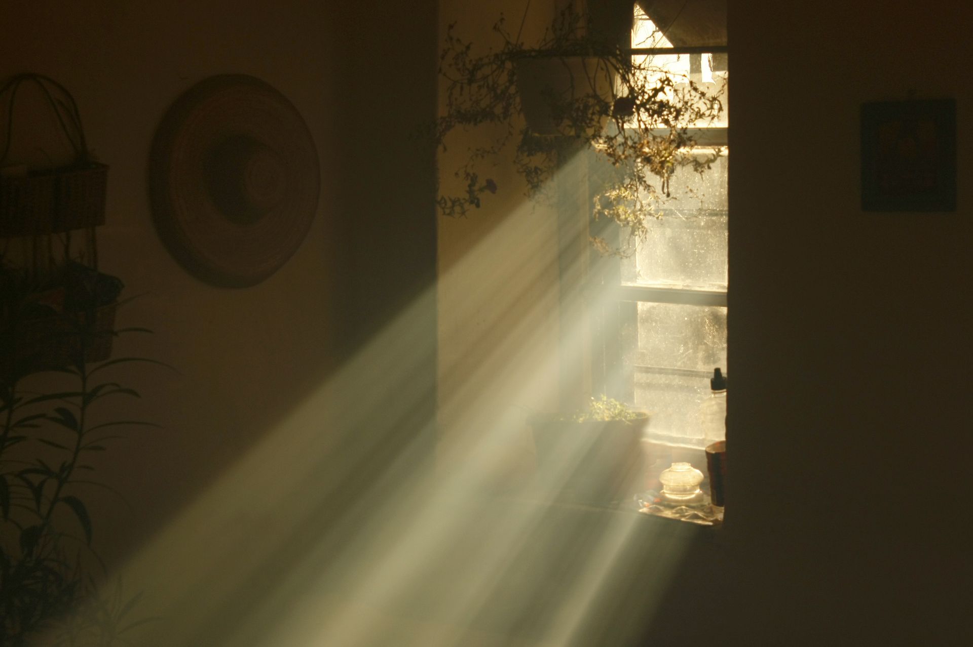 The sun is shining through a window in a dark room.