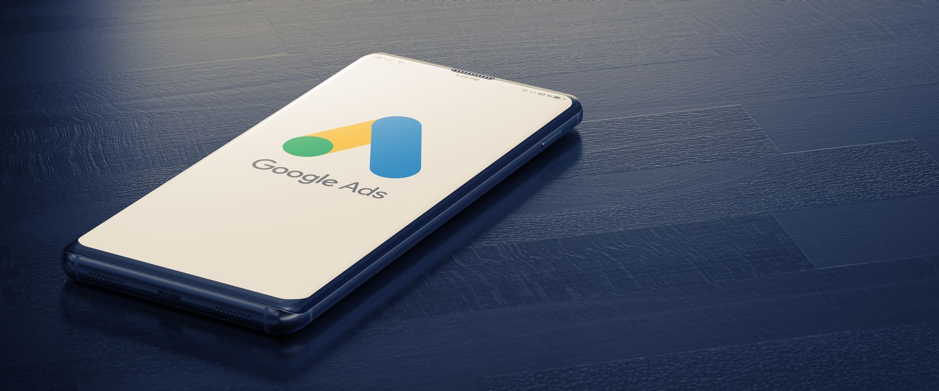 A cell phone with the google ads logo on it is sitting on a blue surface.