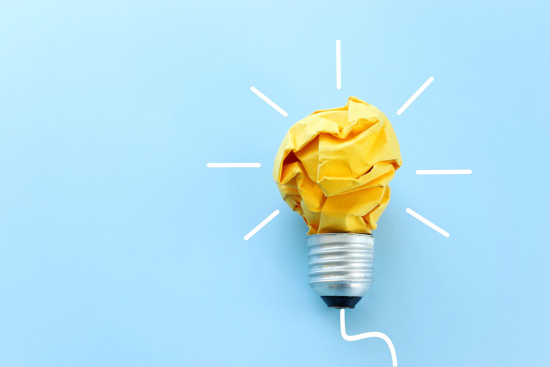 A light bulb made of crumpled paper on a blue background.