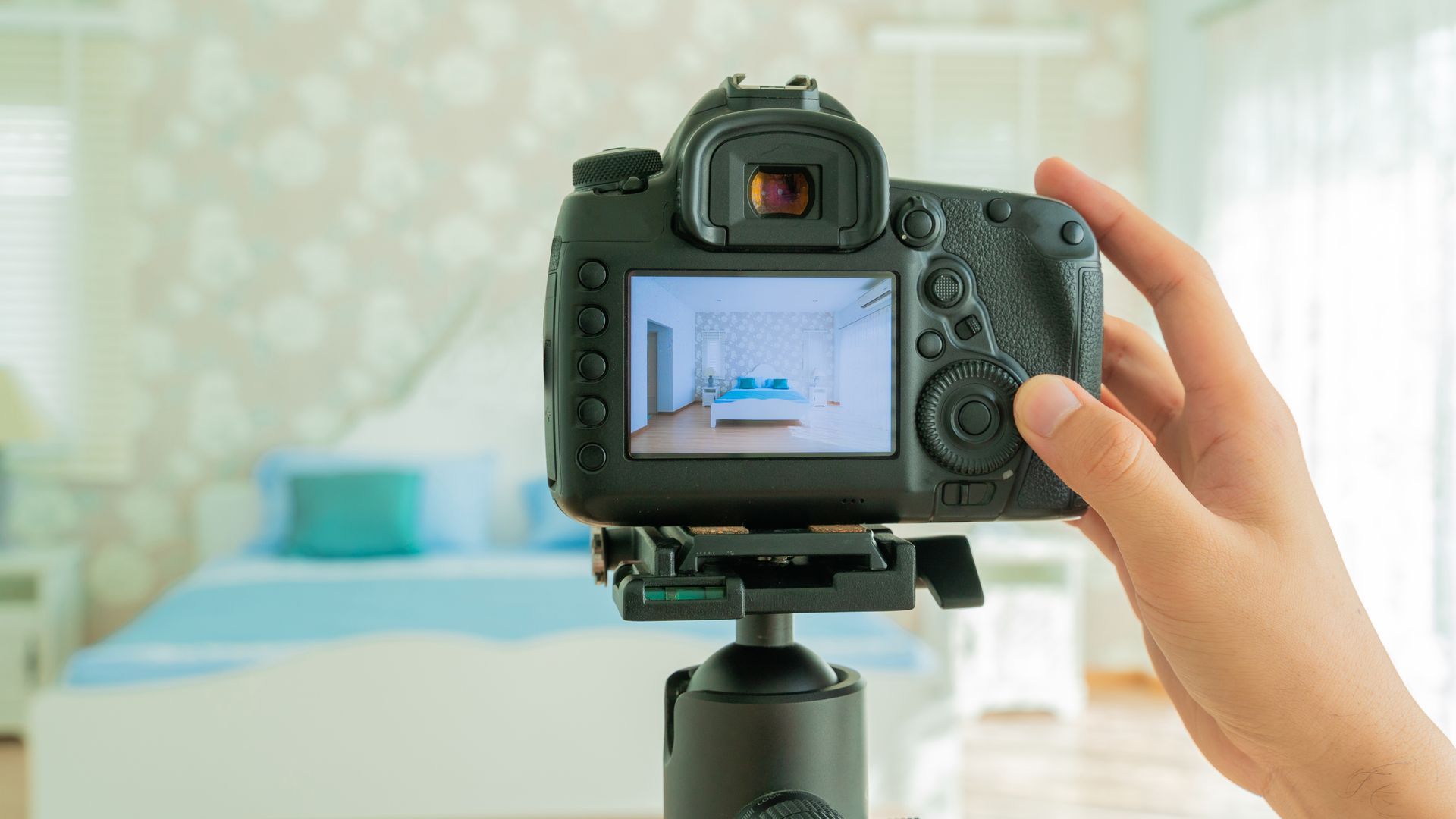 A person is taking a picture of a bedroom with a camera.