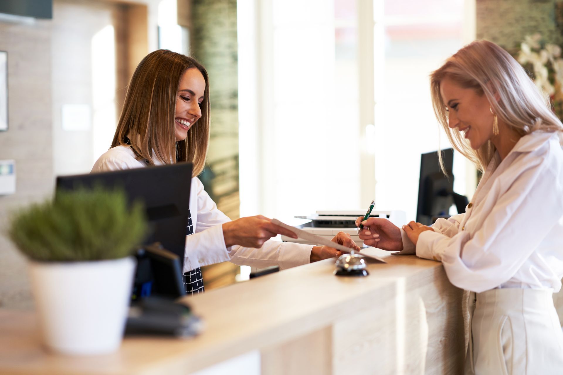 Two women are standing at a counter in a hotel.