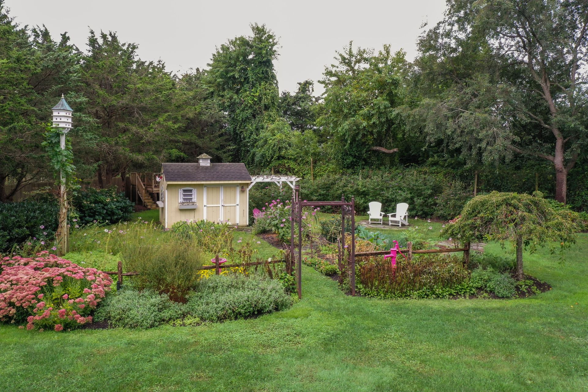 There is a shed in the middle of a garden surrounded by trees.