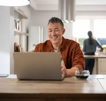 elderly couple looking at a laptop, nearby a campfire and an RV