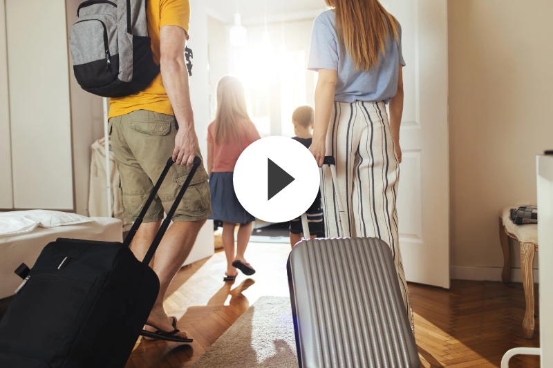 A family is walking into a room with luggage.