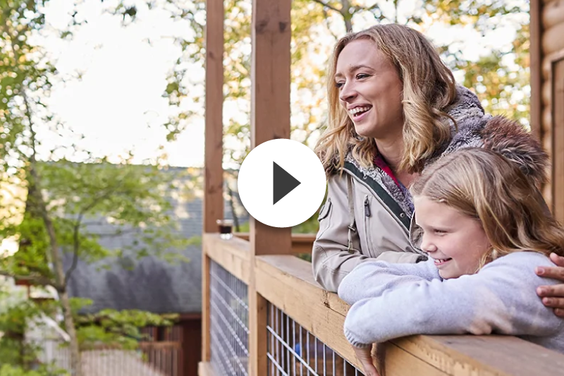 A woman and a little girl are sitting on a porch.