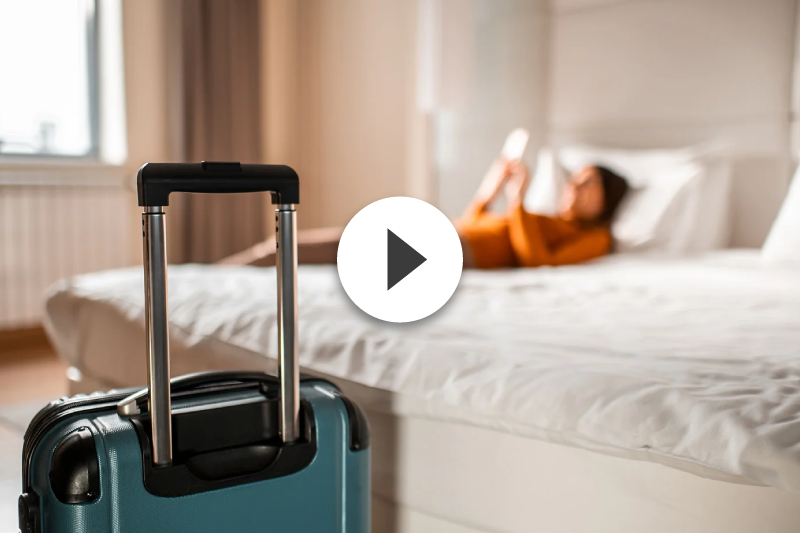 A woman is laying on a bed with a suitcase in front of her.