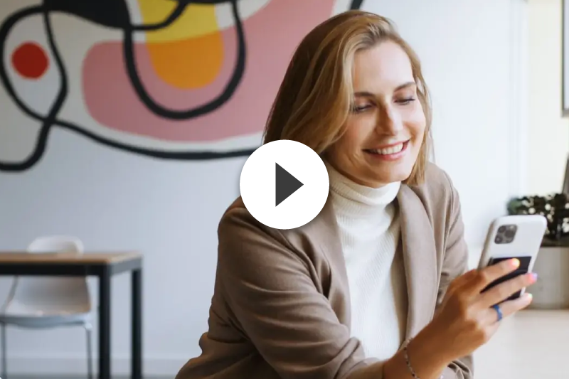 A woman is smiling while looking at her cell phone