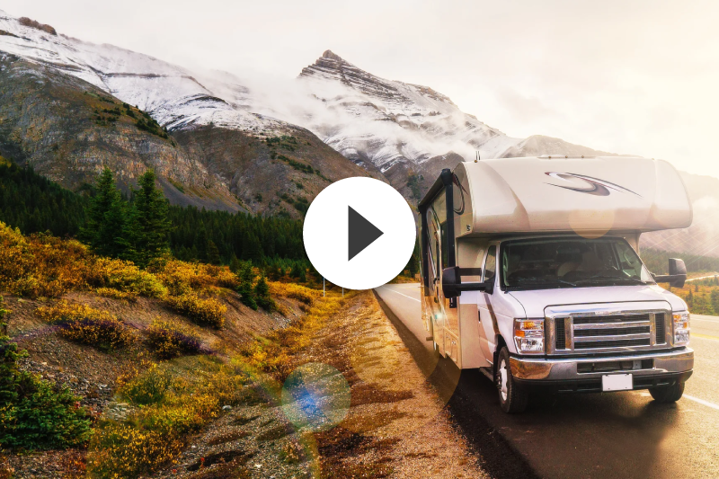 A white rv is driving down a mountain road.