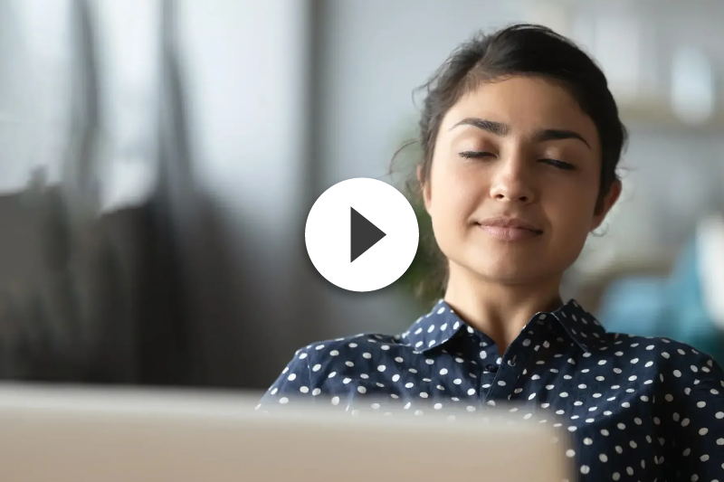 A woman is sitting in front of a laptop computer with her eyes closed.