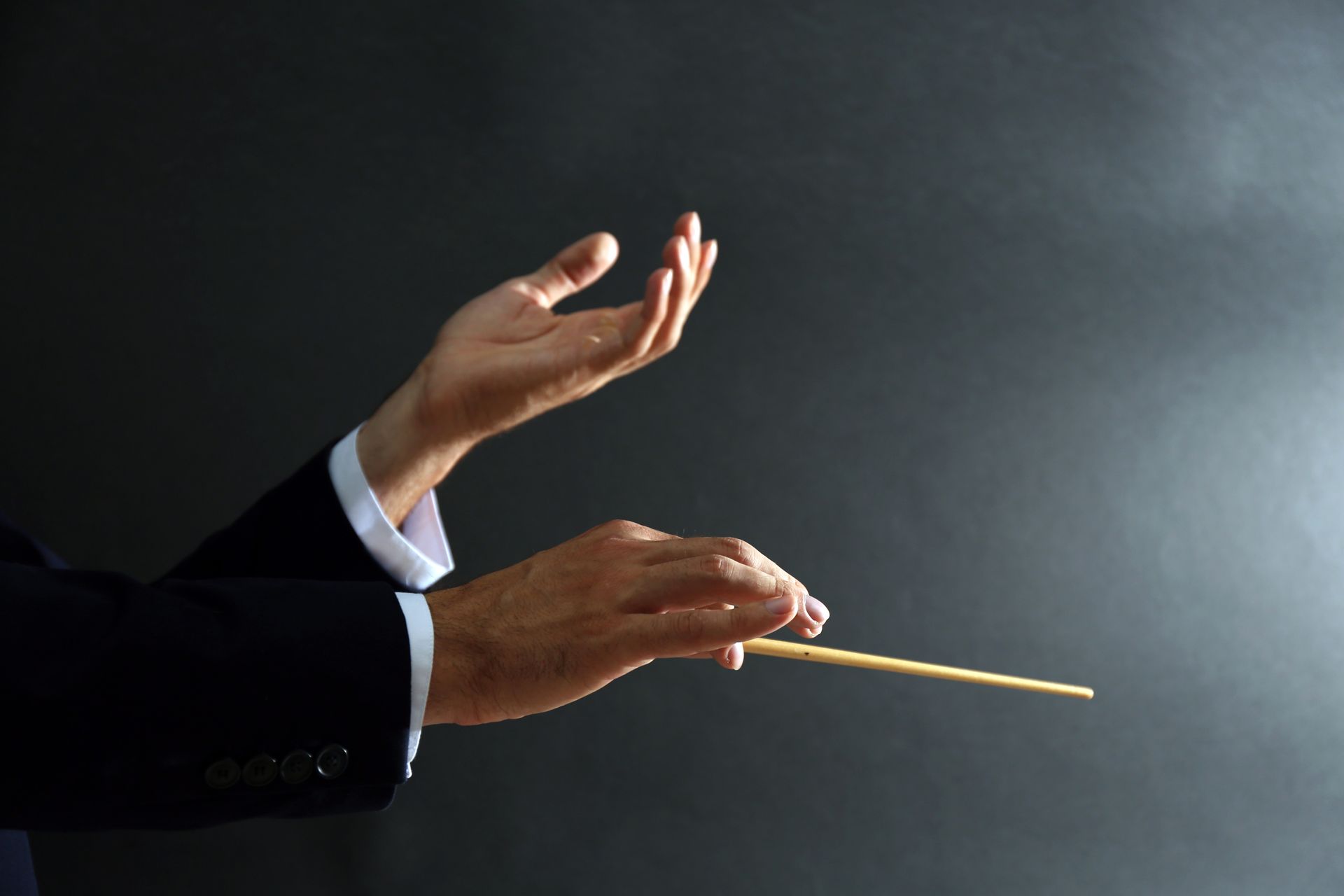 A man in a suit is holding a baton in his hands.