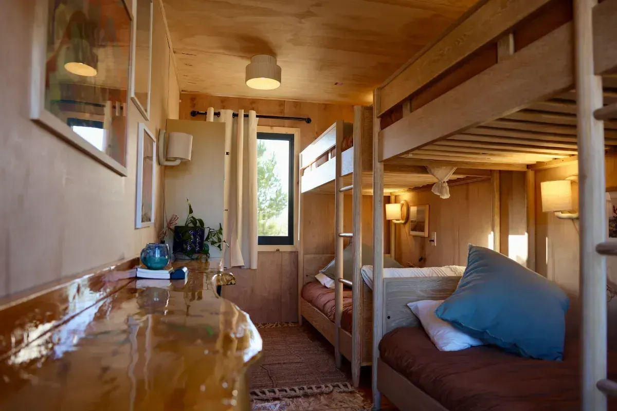 A room with bunk beds , a desk , and a window.