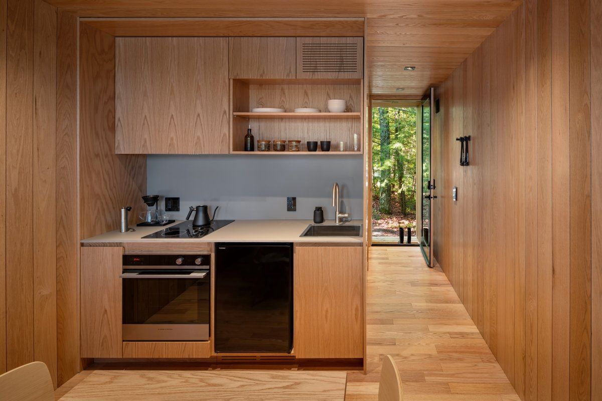 A kitchen with wooden cabinets , a stove , a sink , and a table.