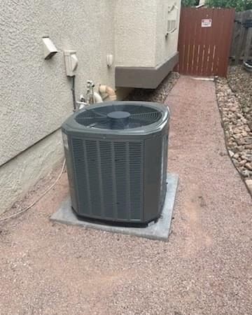 A large air conditioner is sitting on the side of a house.