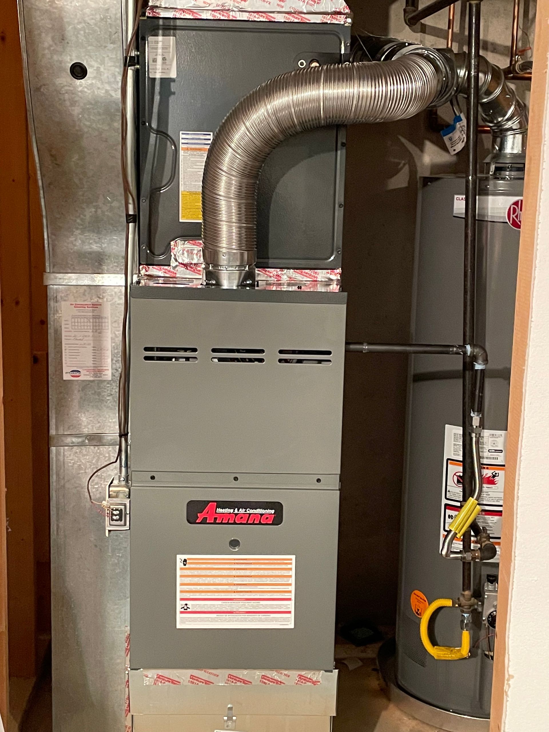 An air conditioner is sitting next to a water heater in a room.