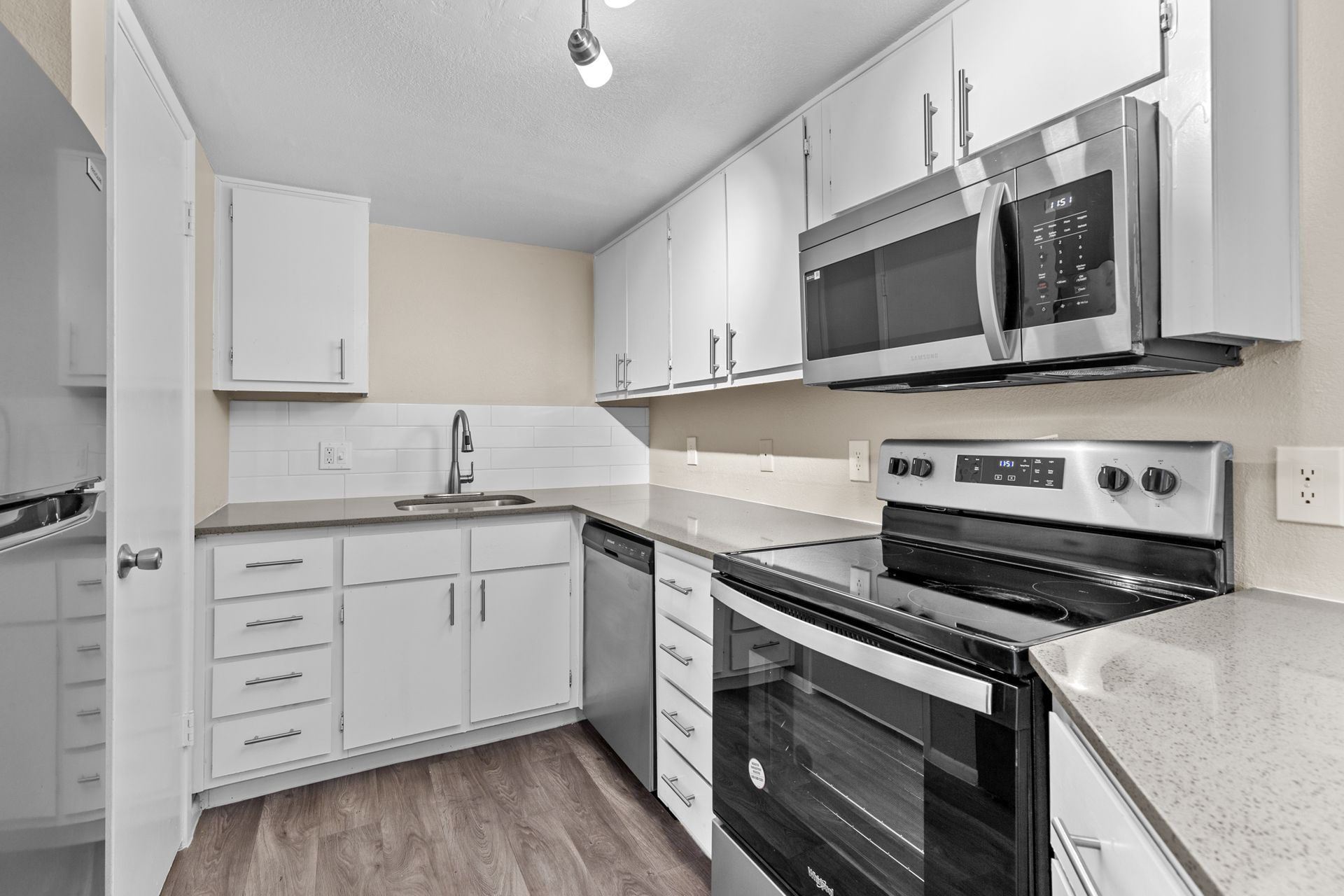 A kitchen with stainless steel appliances and white cabinets at Citrine on 67th.