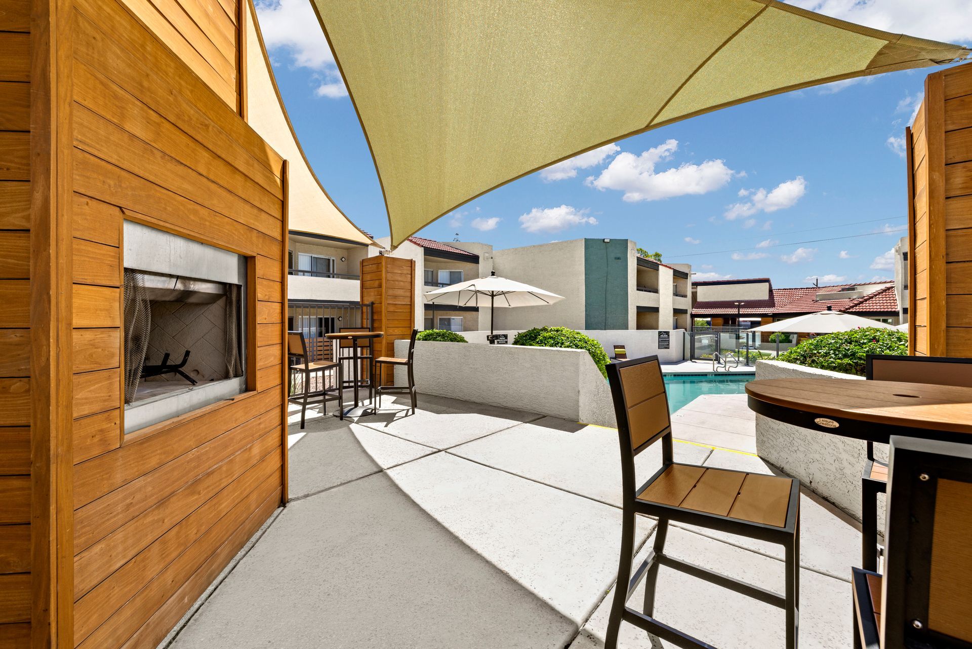 A patio with a table and chairs under an umbrella and a fireplace at Citrine on 67th.