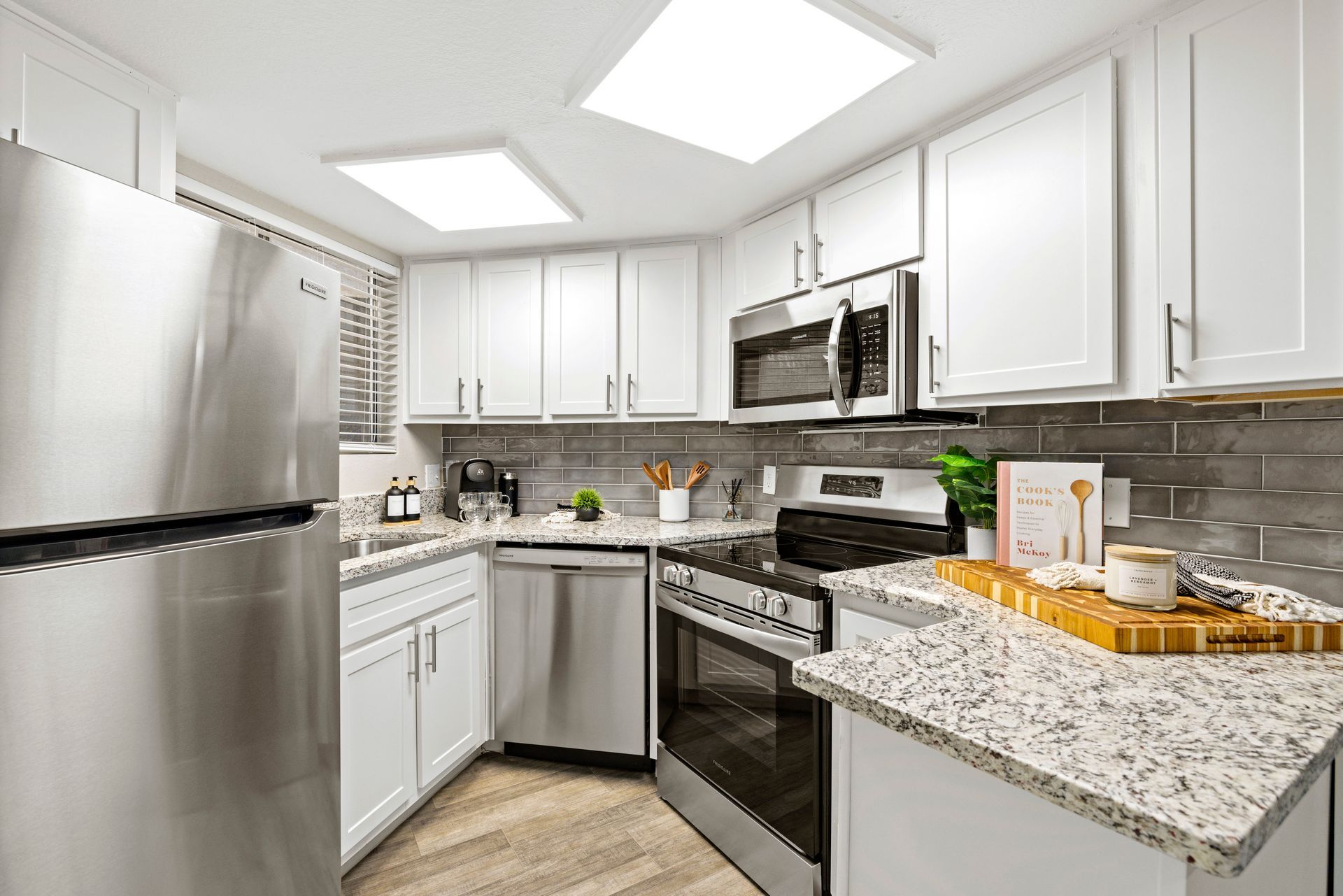 A kitchen with stainless steel appliances and white cabinets at Citrine on 67th.