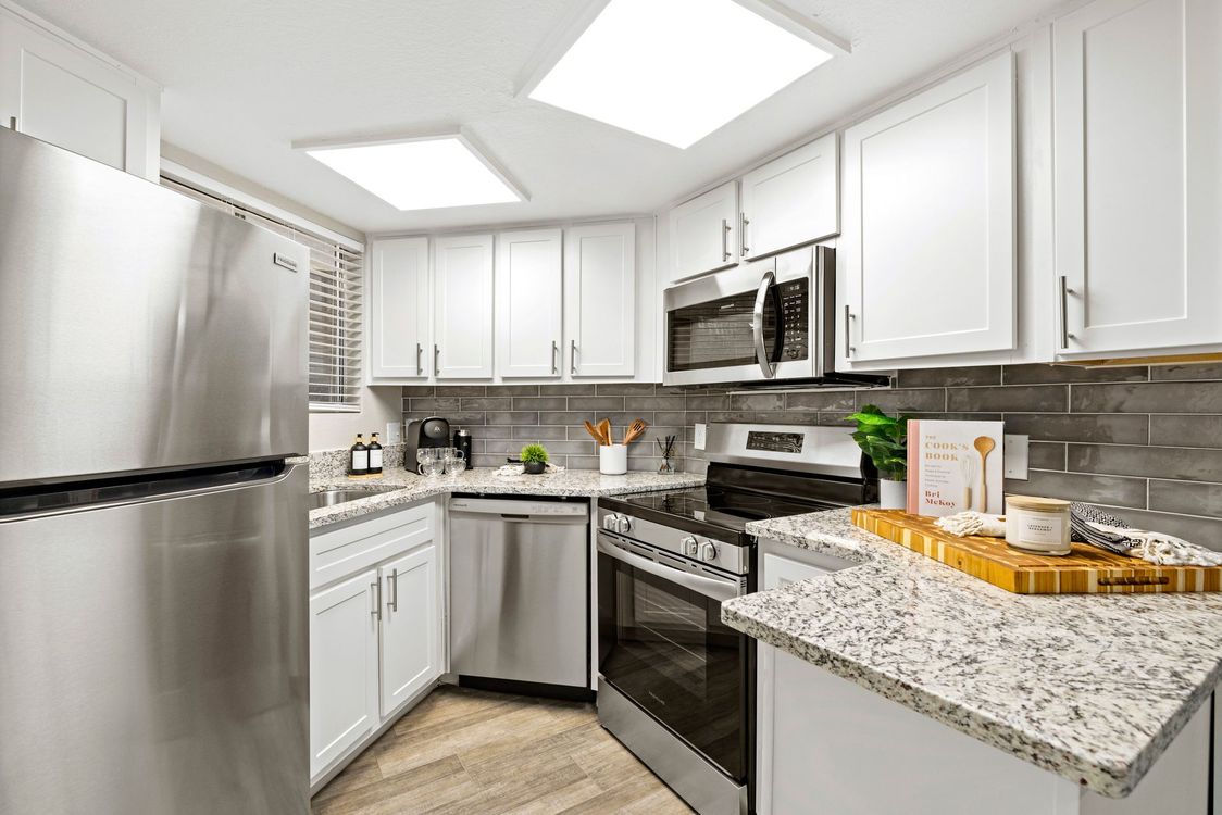 A kitchen with stainless steel appliances and white cabinets at Citrine on 67th.