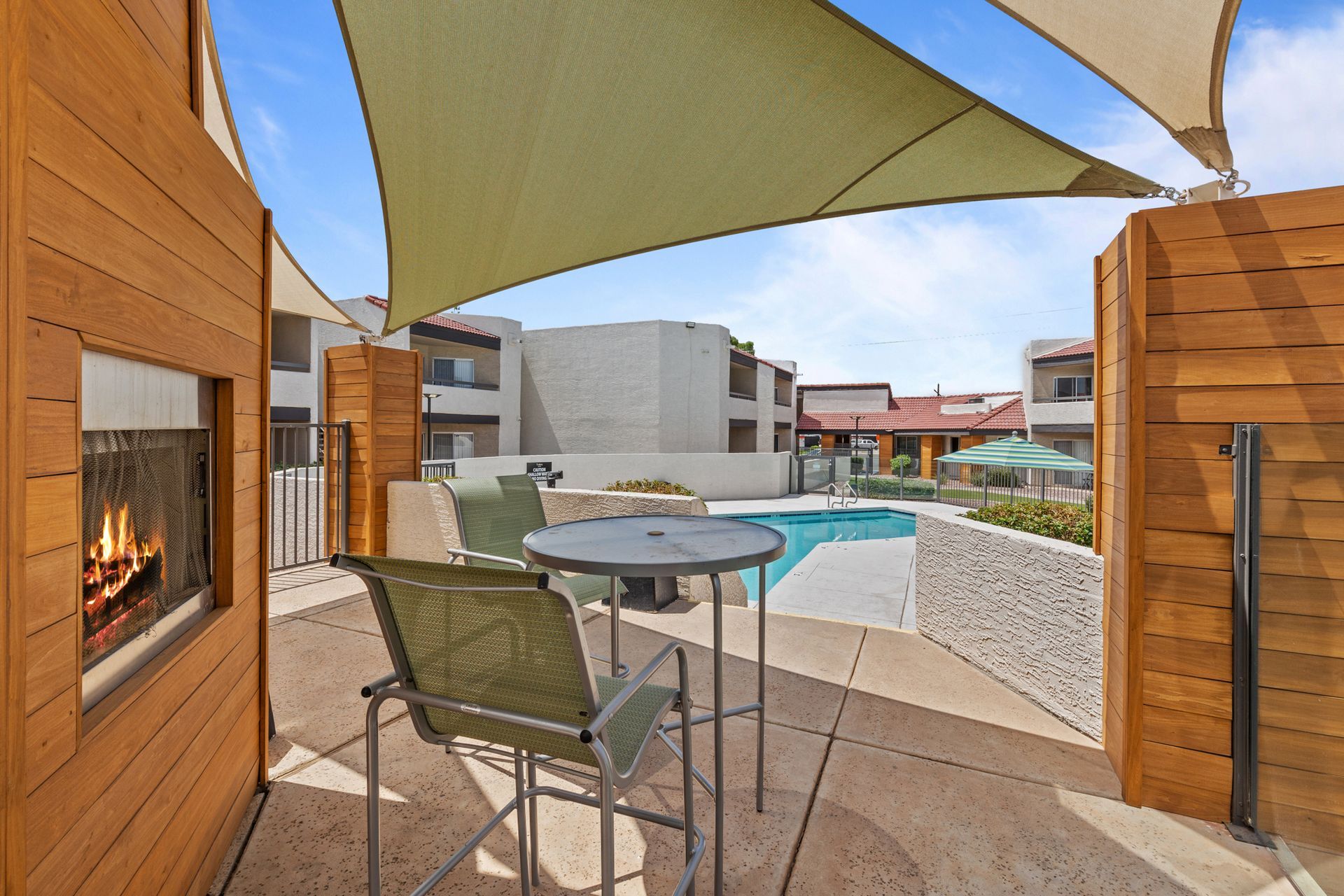 A patio with a table and chairs under an umbrella and a fireplace at Citrine on 67th.