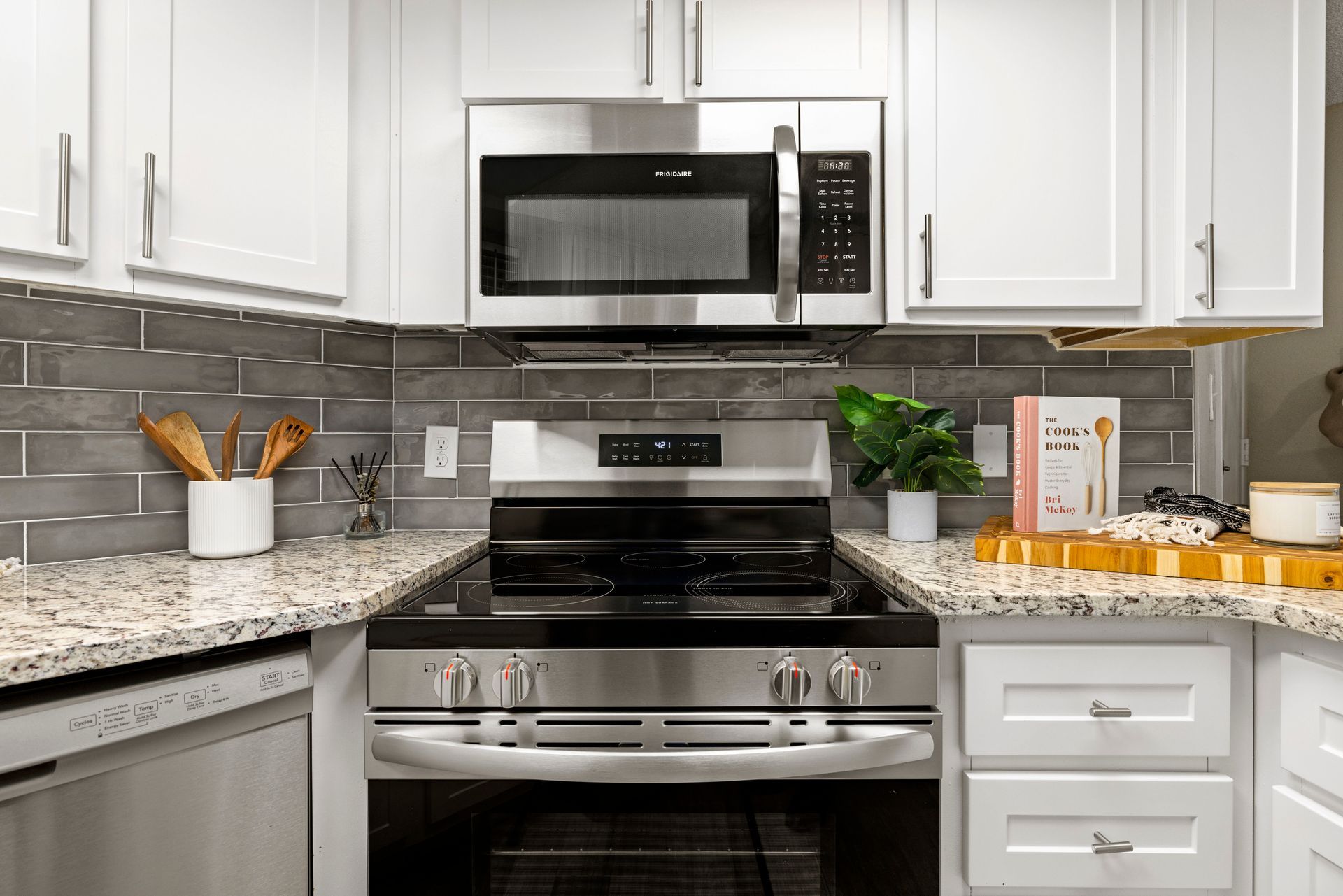 A kitchen with stainless steel appliances and white cabinets at Citrine on 67th.