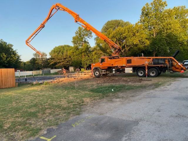 An orange concrete pump truck is parked in a parking lot.