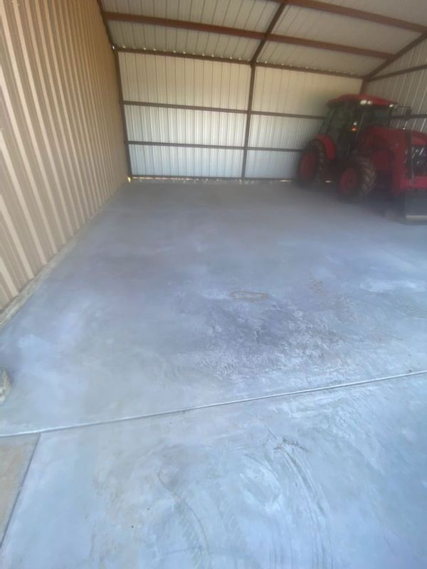 A tractor is parked in a garage with a concrete floor.
