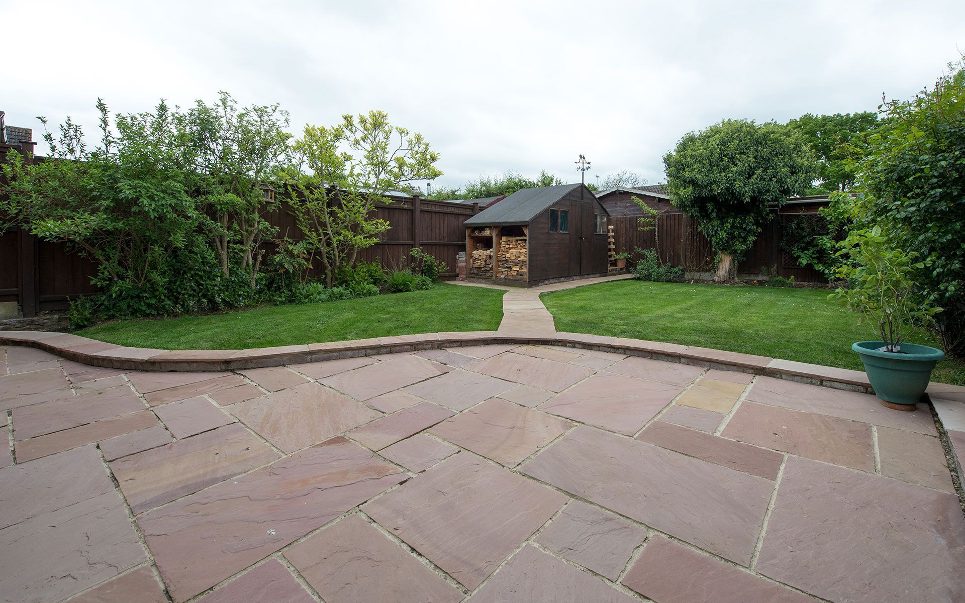 A patio in a backyard with a shed in the background