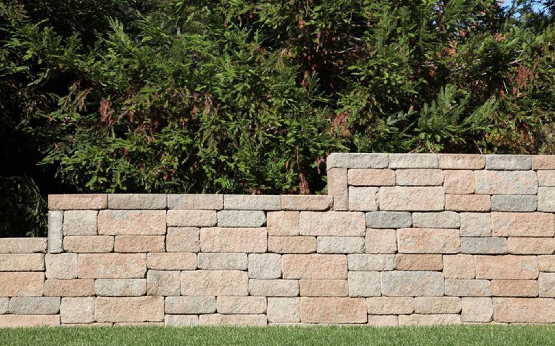 A brick wall is sitting on top of a lush green lawn.