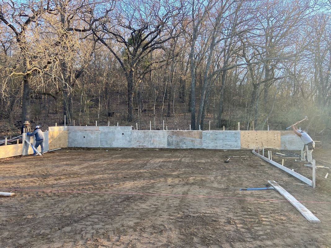A concrete wall is being built in the middle of a dirt field.