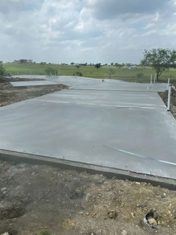 A concrete driveway is being built in a field.