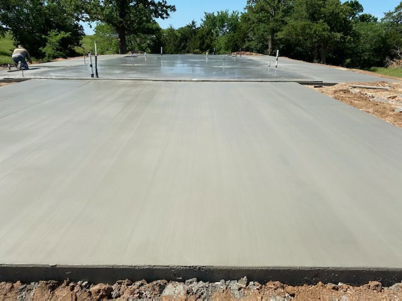 A concrete driveway is being built with trees in the background