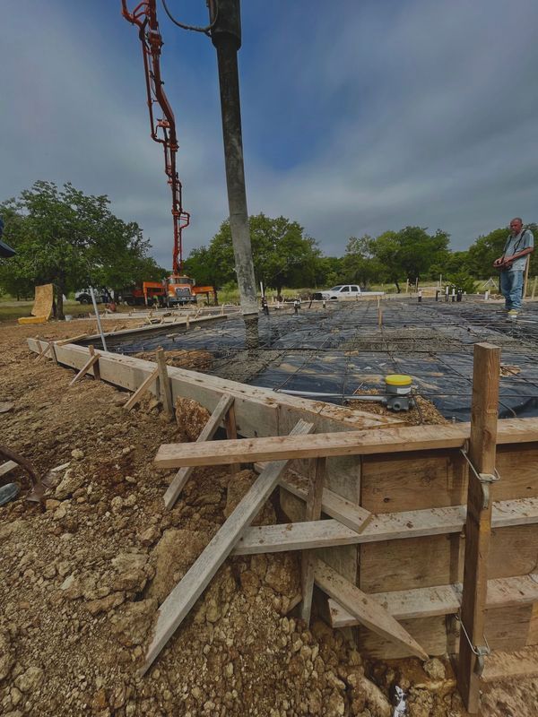 A concrete pump is being used to pour concrete into a foundation.