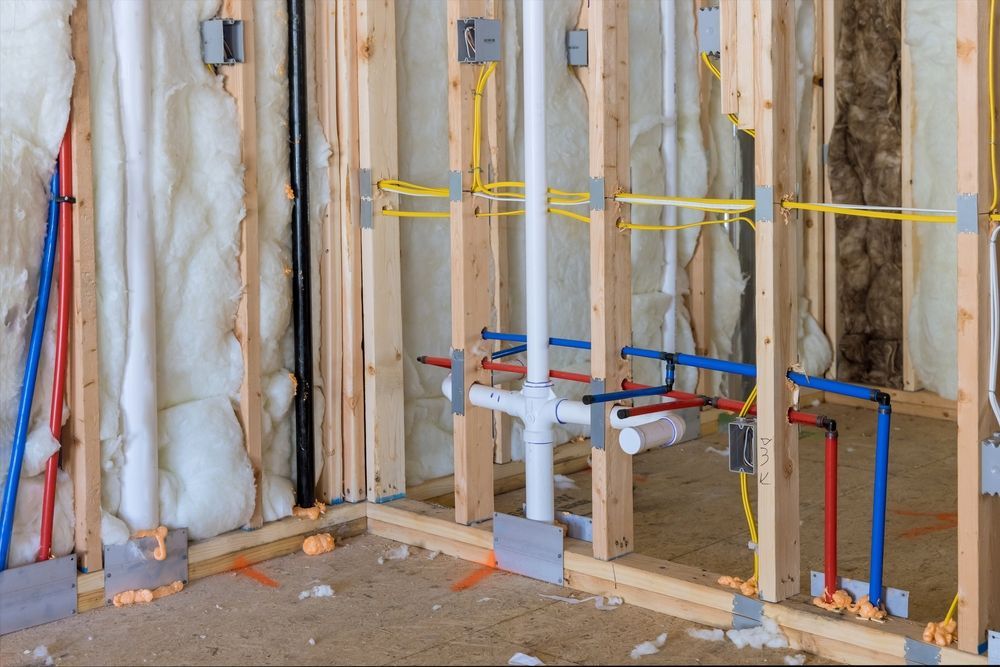 A room in a house under construction with pipes and electrical wires.
